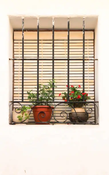 Photo of Whitewashed facade with window with forged metal grill