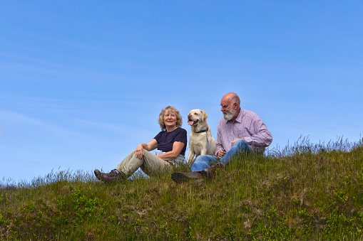 Senior couple resting with their dog whilst walking in Derbyshire's Peak District.