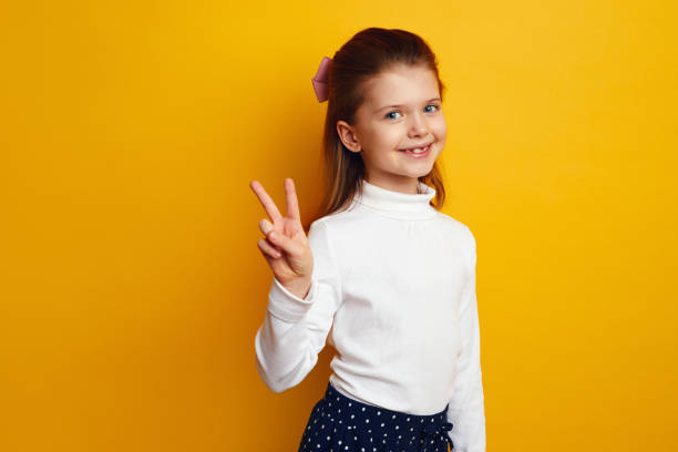 istock Optimistic cute girl kid showing peace gesture against bright yellow background 1324104737