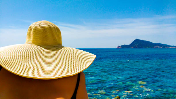 istock Woman in big white hat on the beach 1324110650