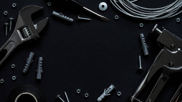 Happy fathers day banner concept. Upholstery repair working tool stapler, screwdriver, screws, adjustable wrench, electrical tape and wire on black background, top view, flat lay, copy space concepto de pancarta del día del padre feliz. reparación de tapicería herramienta de trabajo grapadora, destornillador, tornillos, llave ajustable, cinta eléctrica y alambre sobre fondo negro, vista superior, lay plana, espacio de copia.