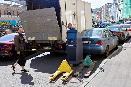 St. Petersburg, Russia - June 16, 2021: Loading an ATM into truck on city street.