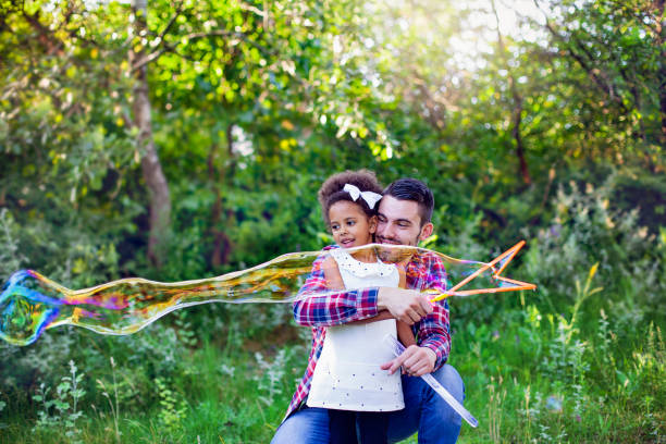 istock Happy father and daughter playing soap bubbles in park. 1324118027
