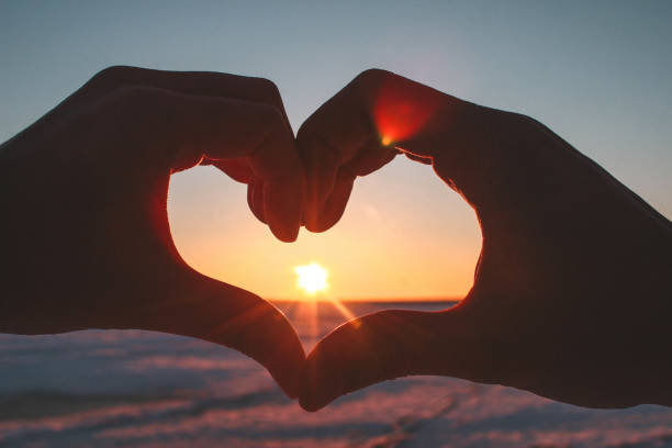 istock A couple making a heart shape with their hands while watching sunset 1324118799
