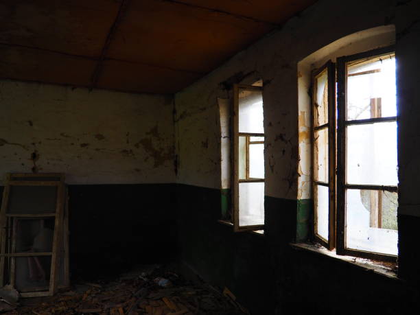 istock Scary windows. Inside an abandoned house. View of broken windows without a curtain. Grunge scene. Light shines through old wooden frames with broken glass. The concept of abandonment and uselessness 1324123147