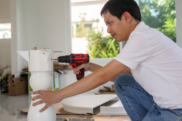 istock Asian man assembling white table furniture at home using cordless screwdriver 1324123233