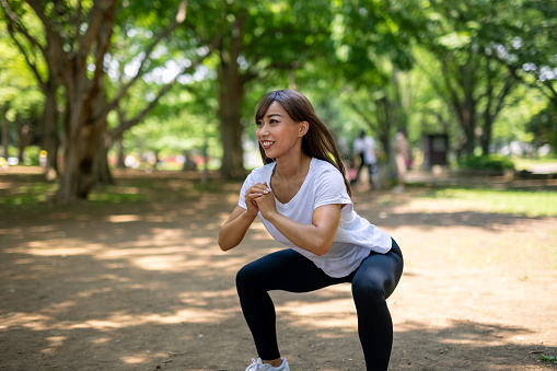 Japanese young female athlete exercising in public park. Stretching, jogging, etc.