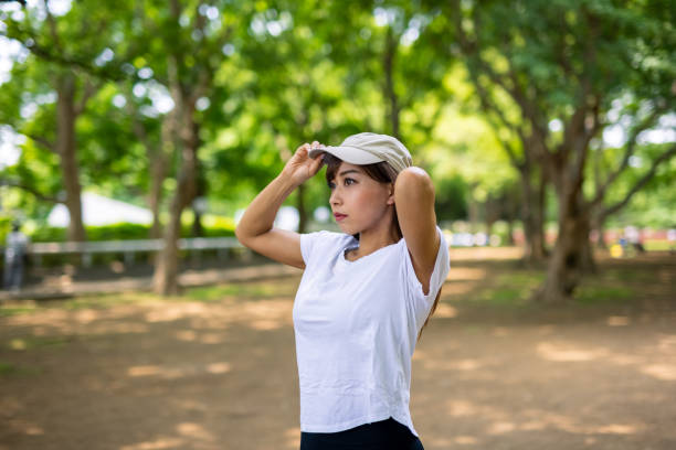 istock Young female athlete putting on cap in public park 1324125729