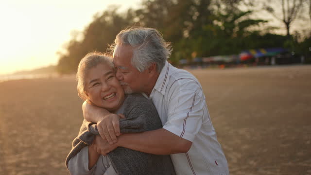 Asian senior couple enjoy romantic vacation on the beach at summer sunset