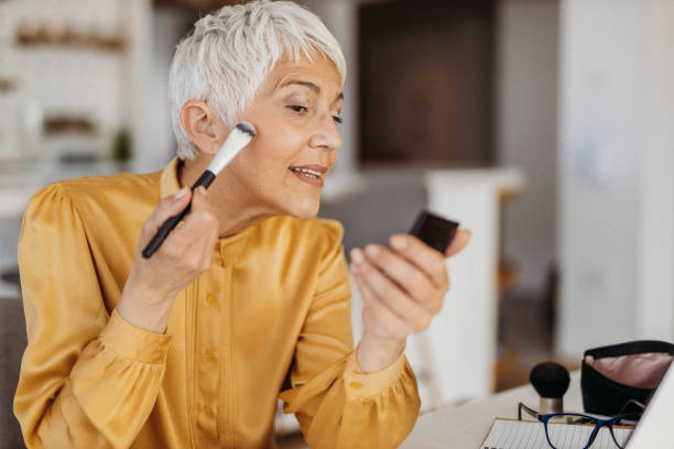 Senior woman working from home Senior woman applying makeup hair care women mature adult human skin stock pictures, royalty-free photos & images