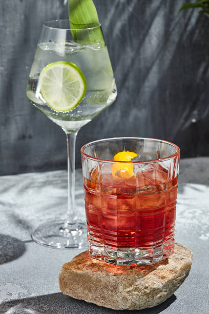Negroni cocktail on stone podium. Sunshine with harsh shadow on vintage table. Summer day with cocktail concept. Vermouth with gin cocktail Negroni cocktail on stone podium. Sunshine with harsh shadow on vintage table. Summer day with cocktail concept. Vermouth with gin cocktail Gin stock pictures, royalty-free photos & images