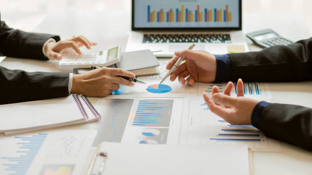 istock Businessmen discuss charts and analyze graphs showing successful teamwork on a desk with laptop and calculator. 1324133565