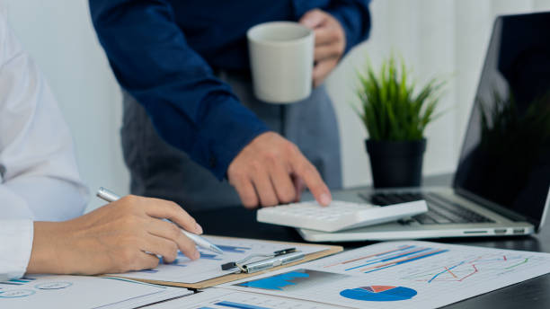 istock Businessmen discuss charts and analyze graphs showing successful teamwork on a desk with laptop and calculator. 1324134440