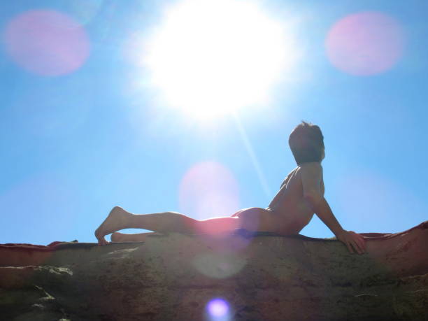 nackter mann posiert in der sonne am felsigen strand - yoga nudist silhouette naked stock-fotos und bilder