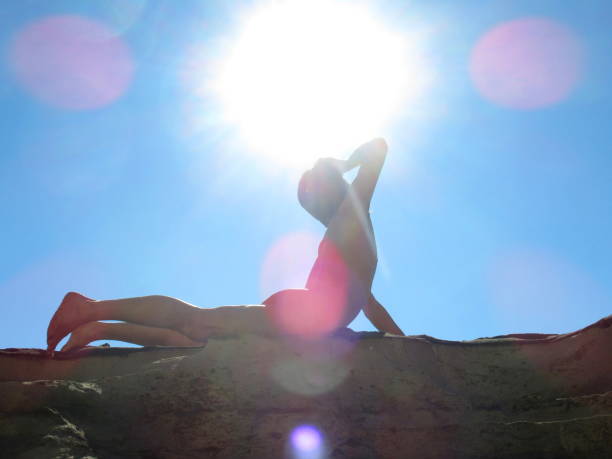 naked man posing in the sun on rocky beach - yoga nudist silhouette naked imagens e fotografias de stock