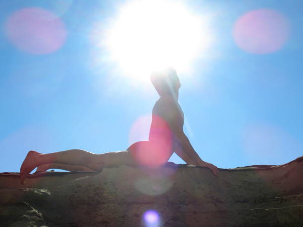naked man posing in the sun on rocky beach - yoga nudist silhouette naked imagens e fotografias de stock