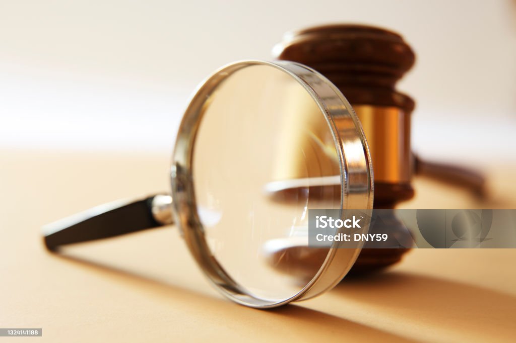 Magnifying Glass And Gavel A gavel seen through a magnifying glass.  Photographed with a very shallow depth of field. Legal System Stock Photo