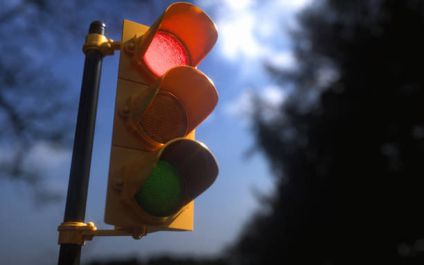 Outdoor Vertical Traffic Light Red Color Outdoor vertical traffic light with blue sky and trees around. Traffic control concept image with shallow depth of field. blue yellow lights stock pictures, royalty-free photos & images