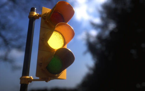 Outdoor Vertical Traffic Light Yellow Color Outdoor vertical traffic light with blue sky and trees around. Traffic control concept image with shallow depth of field. blue yellow lights stock pictures, royalty-free photos & images