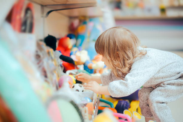 Happy Toddler Girl Choosing a Ball in Toys Store Young customer looking for a toy in kids shop expressing independence and freedom of choice toy store stock pictures, royalty-free photos & images