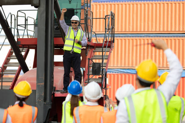 istock warehouse boss engineer standing on crane car with factory workers raise hand for congratulations in containers warehouse storage 1324149233