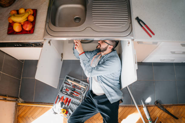 istock Young repairman with tools in his hands is fixing the sink in the kitchen 1324151893