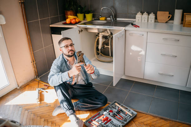 istock Young repairman with tools in his hands is fixing the sink in the kitchen 1324153610