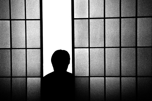 A man' silhouette peeking from a shoji.