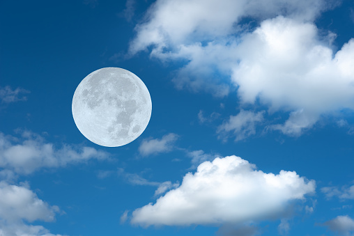 Full moon with clouds on the blue sky.