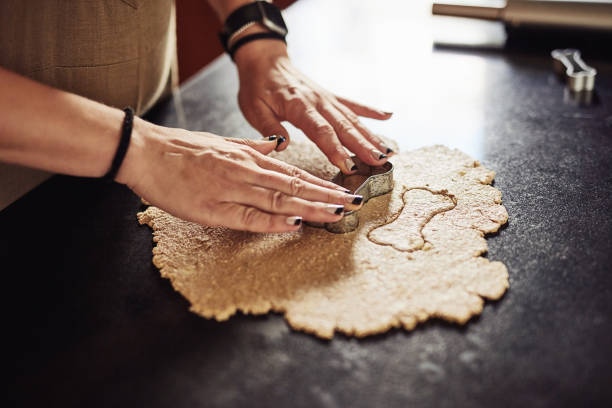 istock Cropped shot of an unrecognizable woman standing alone in her kitchen and using cookie cutters to make dog biscuits 1324162951