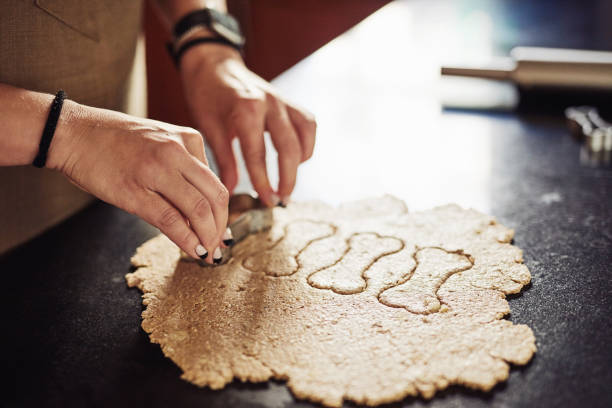 istock Cropped shot of an unrecognizable woman standing alone in her kitchen and using cookie cutters to make dog biscuits 1324162953