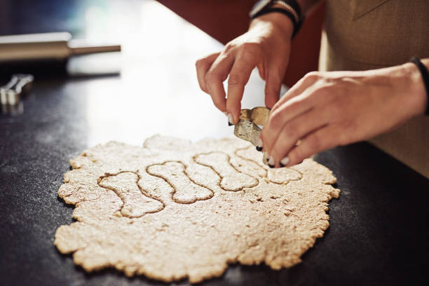 Cropped shot of an unrecognizable woman standing alone in her kitchen and using cookie cutters to make dog biscuits
