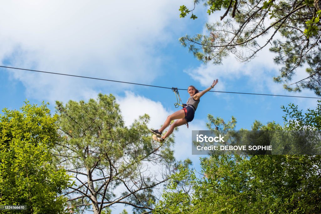 pretty young woman in an extreme tree climbing course pretty young woman in a tree climbing park Zip Line Stock Photo
