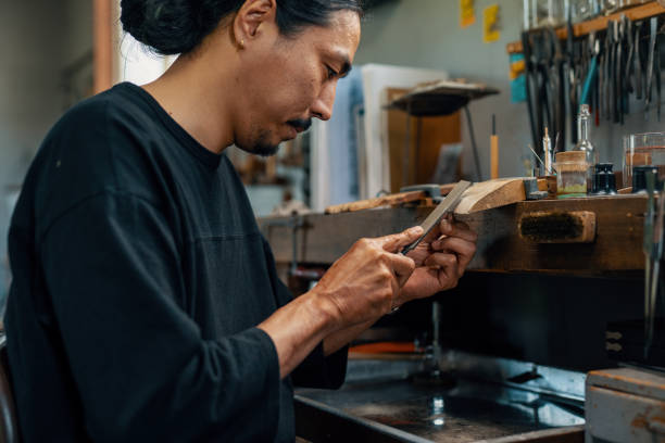 Mid adult silversmith polishing a silver ring by hand