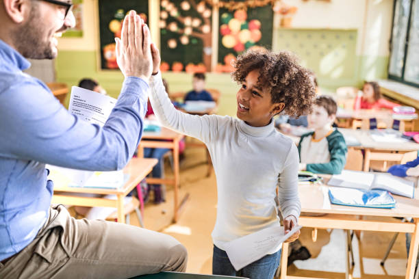 istock Happy black schoolgirl giving her teacher high-five on a class. 1324167843