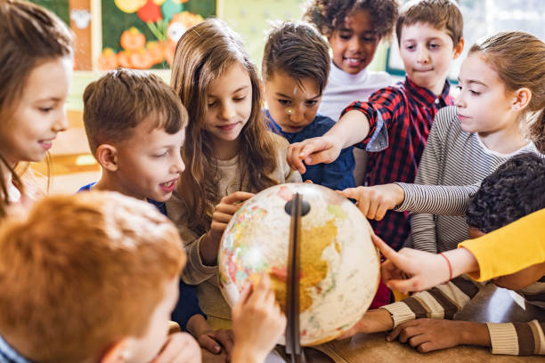 istock Large group of happy students analyzing globe in the classroom. 1324167909