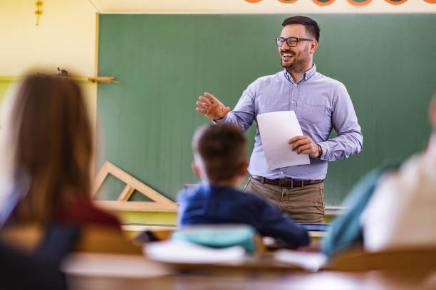 istock Happy male teacher giving a lecture at elementary school. 1324167951