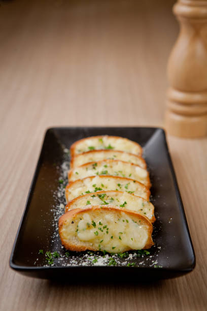 istock Tasty bread with garlic, cheese and herbs on kitchen table 1324168644