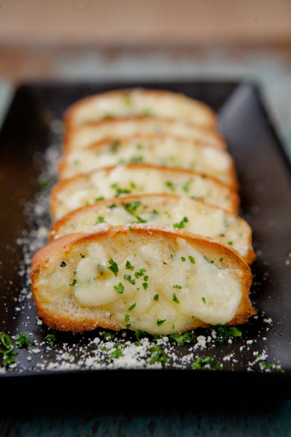 istock Tasty bread with garlic, cheese and herbs on kitchen table 1324168650