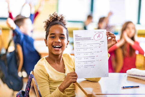 I've got an A on my exam! Happy African American schoolgirl showing her A grade on a test at elementary school and looking at camera. report card stock pictures, royalty-free photos & images