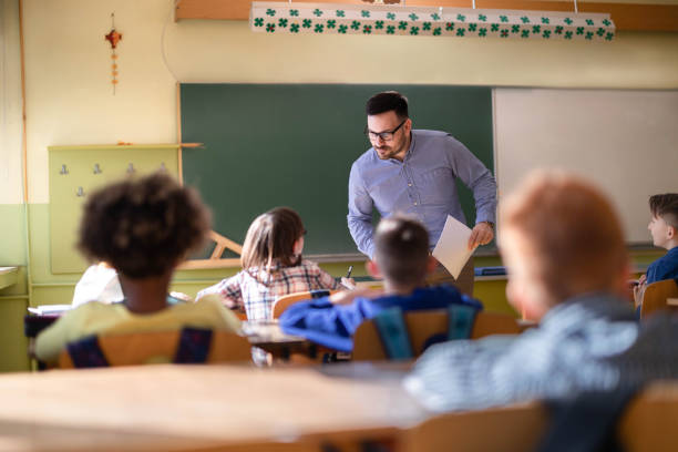 istock Male teacher assisting his student on a class at elementary school. 1324169031