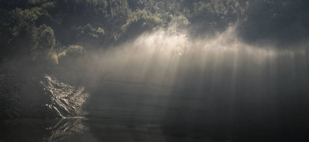 i raggi del sole sfondano i ciuffi di nebbia - portomarin foto e immagini stock
