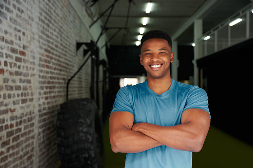 African American male standing with crossed arms in the gym. Male athlete looking intensely at the camera. High quality photo