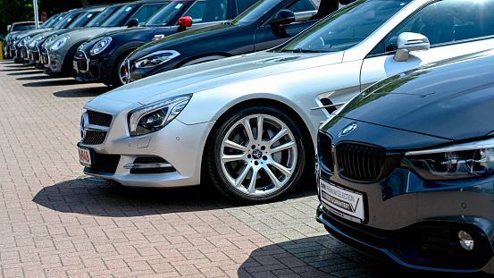 Hamburg, Germany, June 5, 2021 - A Row of modern BMW vehicles and a silver Mercedes SL - closely behind each other - at the public dealership of a car dealer in Hamburg, Germany.