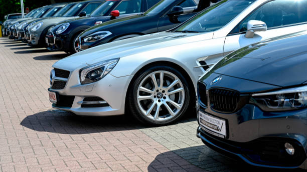 A Row of modern BMW vehicles and a silver Mercedes SL Hamburg, Germany, June 5, 2021 - A Row of modern BMW vehicles and a silver Mercedes SL - closely behind each other - at the public dealership of a car dealer in Hamburg, Germany. mercedes benz photos stock pictures, royalty-free photos & images