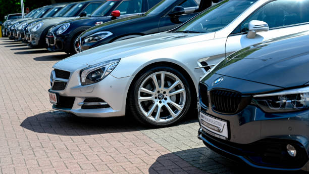 A Row of modern BMW vehicles and a silver Mercedes SL Hamburg, Germany, June 5, 2021 - A Row of modern BMW vehicles and a silver Mercedes SL - closely behind each other - at the public dealership of a car dealer in Hamburg, Germany. bmw dealership stock pictures, royalty-free photos & images