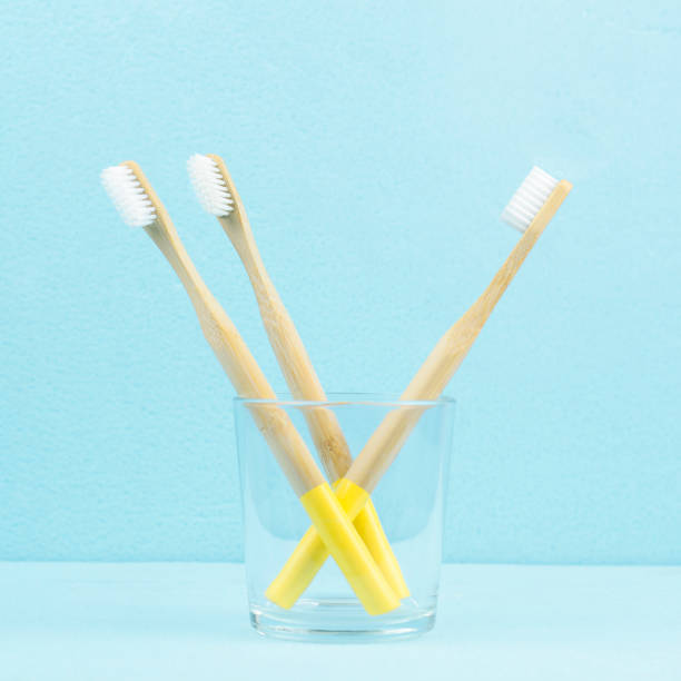 istock Eco-friendly bamboo toothbrushes in a transparent glass on a blue background. Zero waste concept. 1324172672