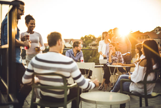 Happy business people having fun on a balcony after work at sunset.