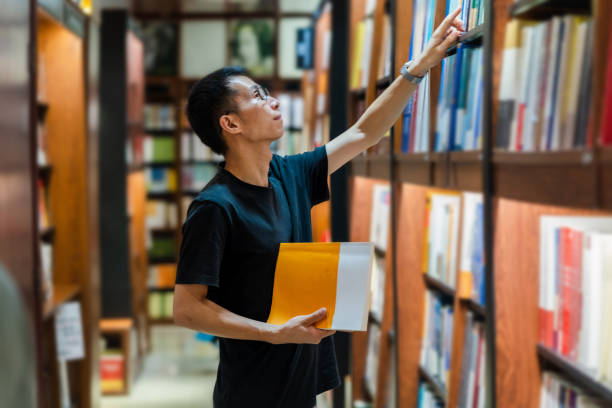 Young Asian woman choosing books in the library