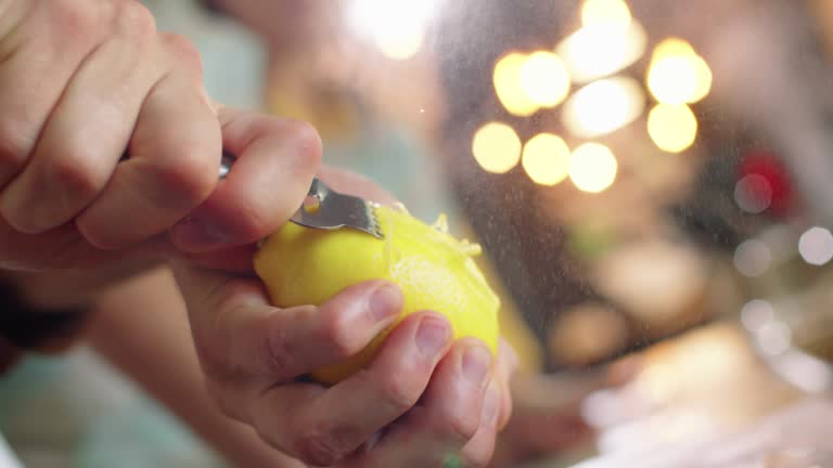 Hands of Chef Zesting Lemon with Citrus Peeler